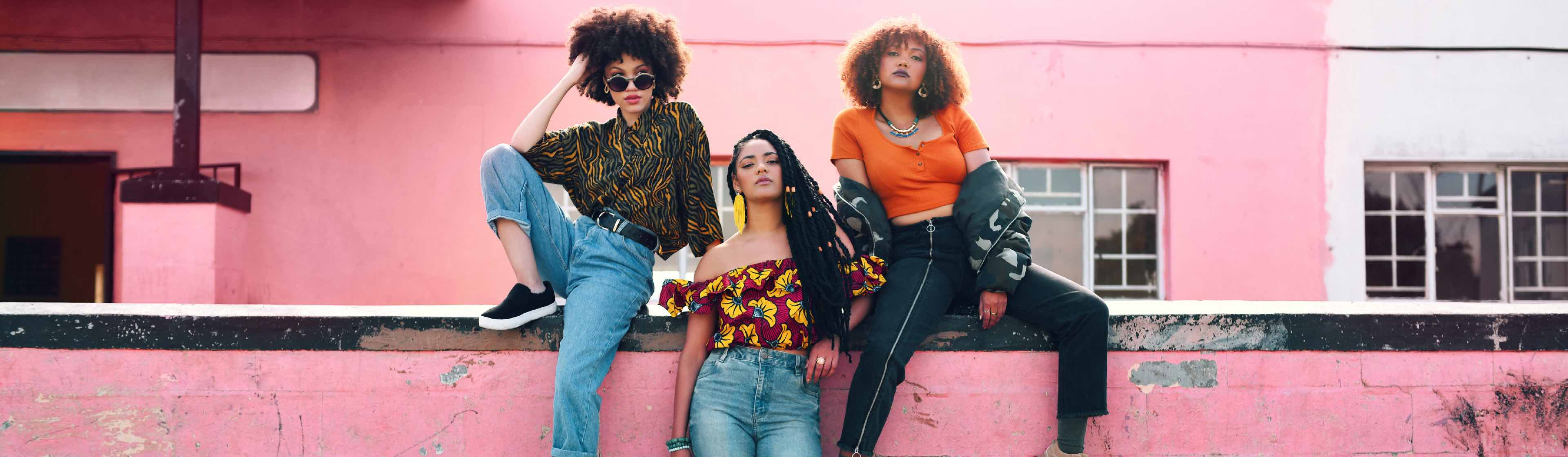 Three South African women posing against a pink wall