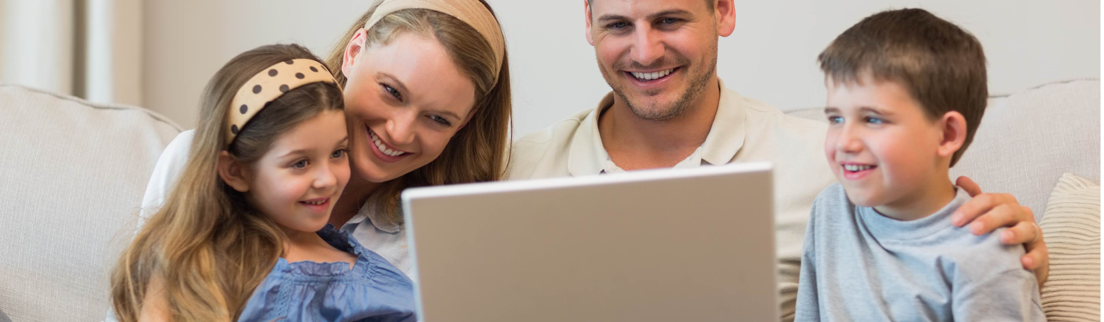 A family of four huddling around a laptop