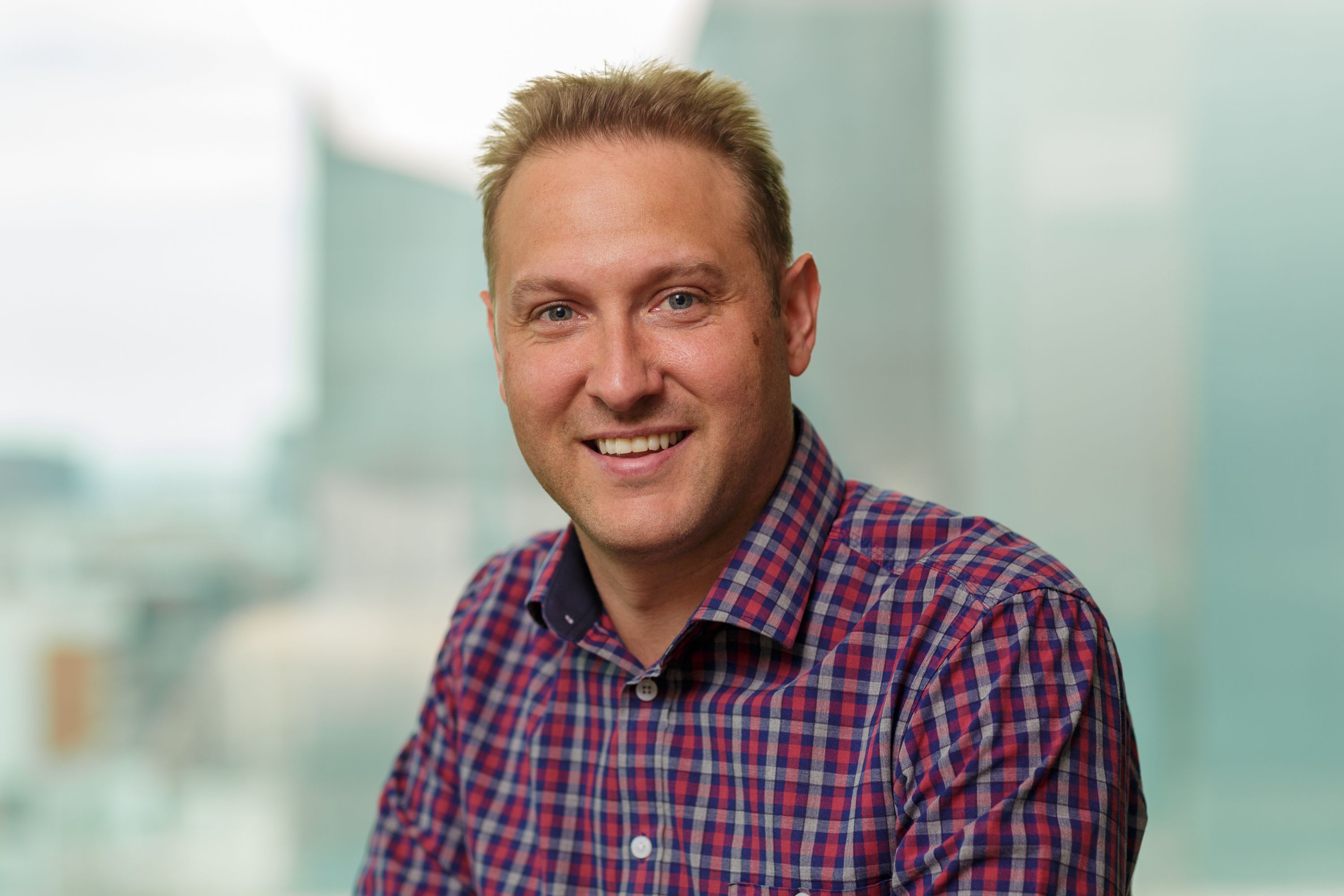 Greg in a chequered shirt smiling 