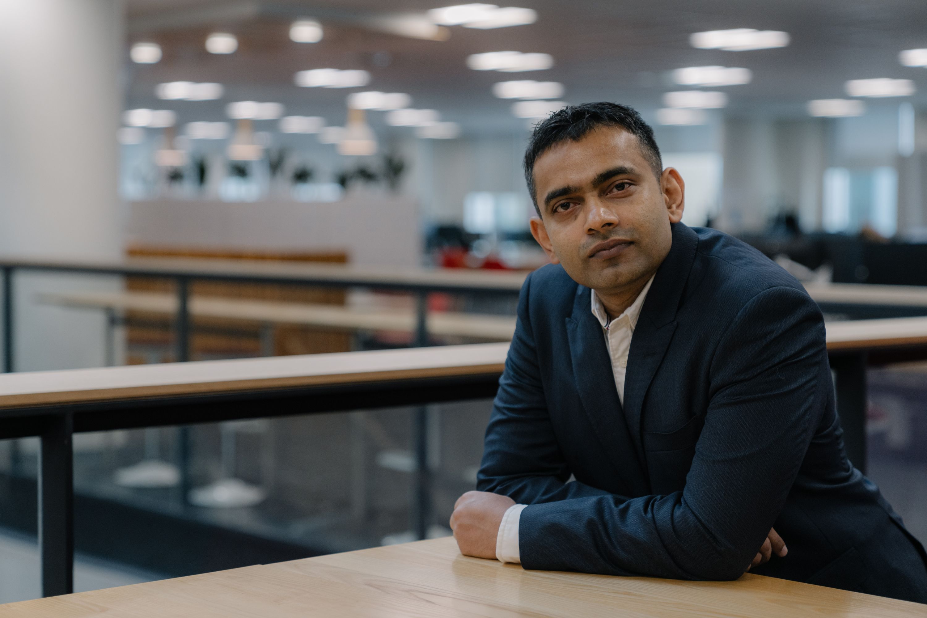 Anish leaning on table wearing a suit