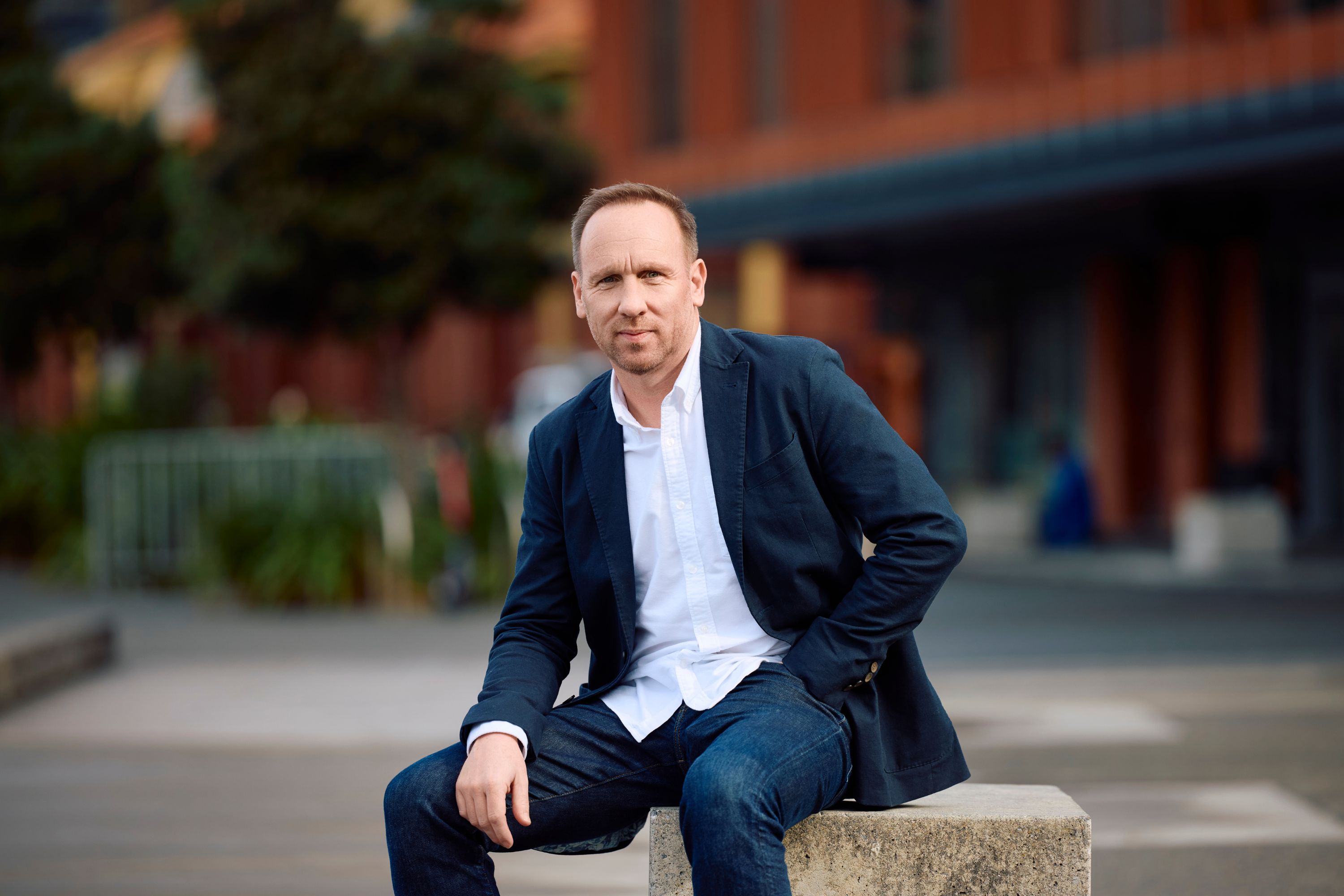 Pat Brogan sitting down in a suit for his profile shot