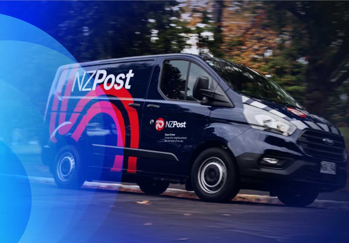 An NZ post van driving on a road next to a park