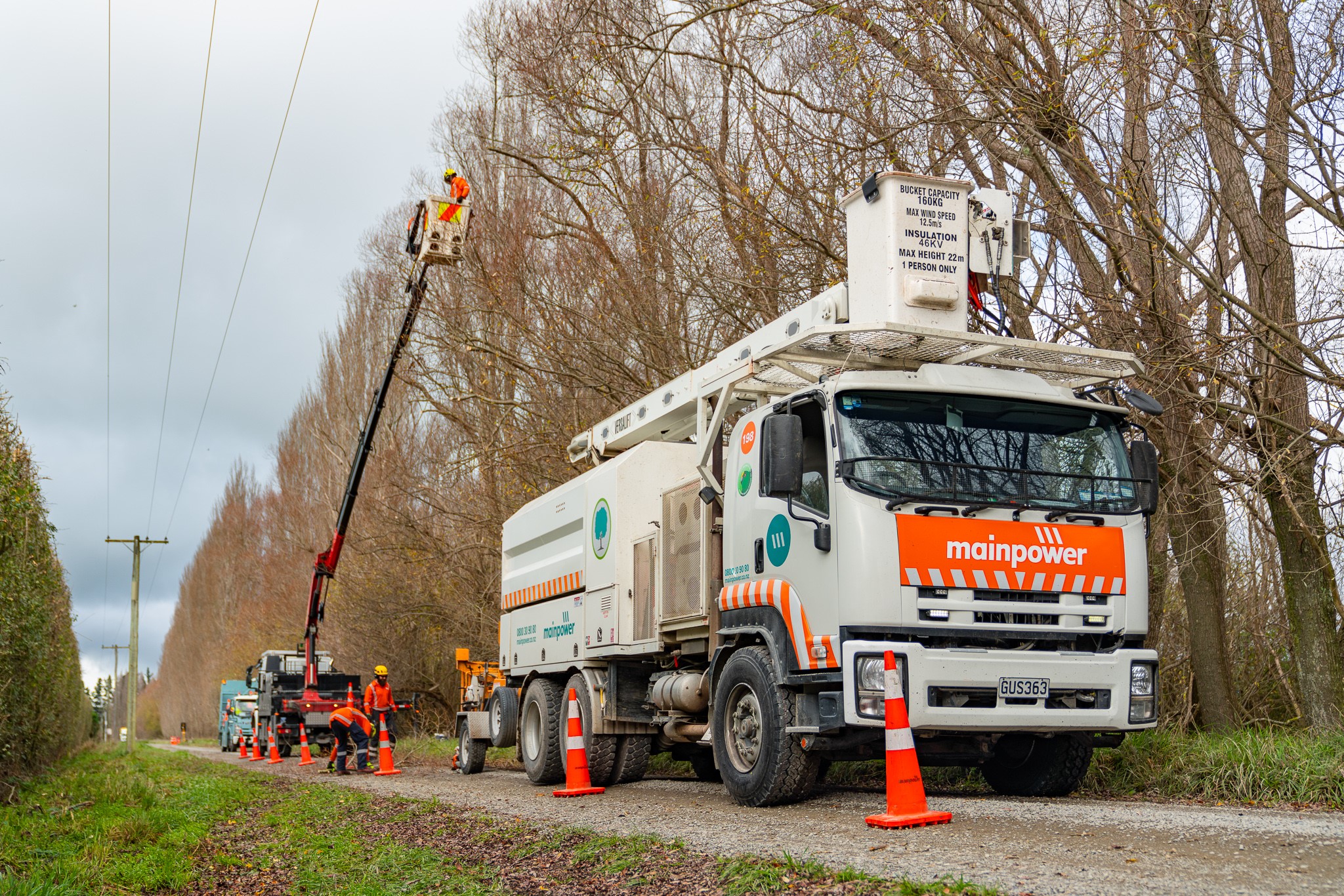 A mainpower truck on a road next to trees