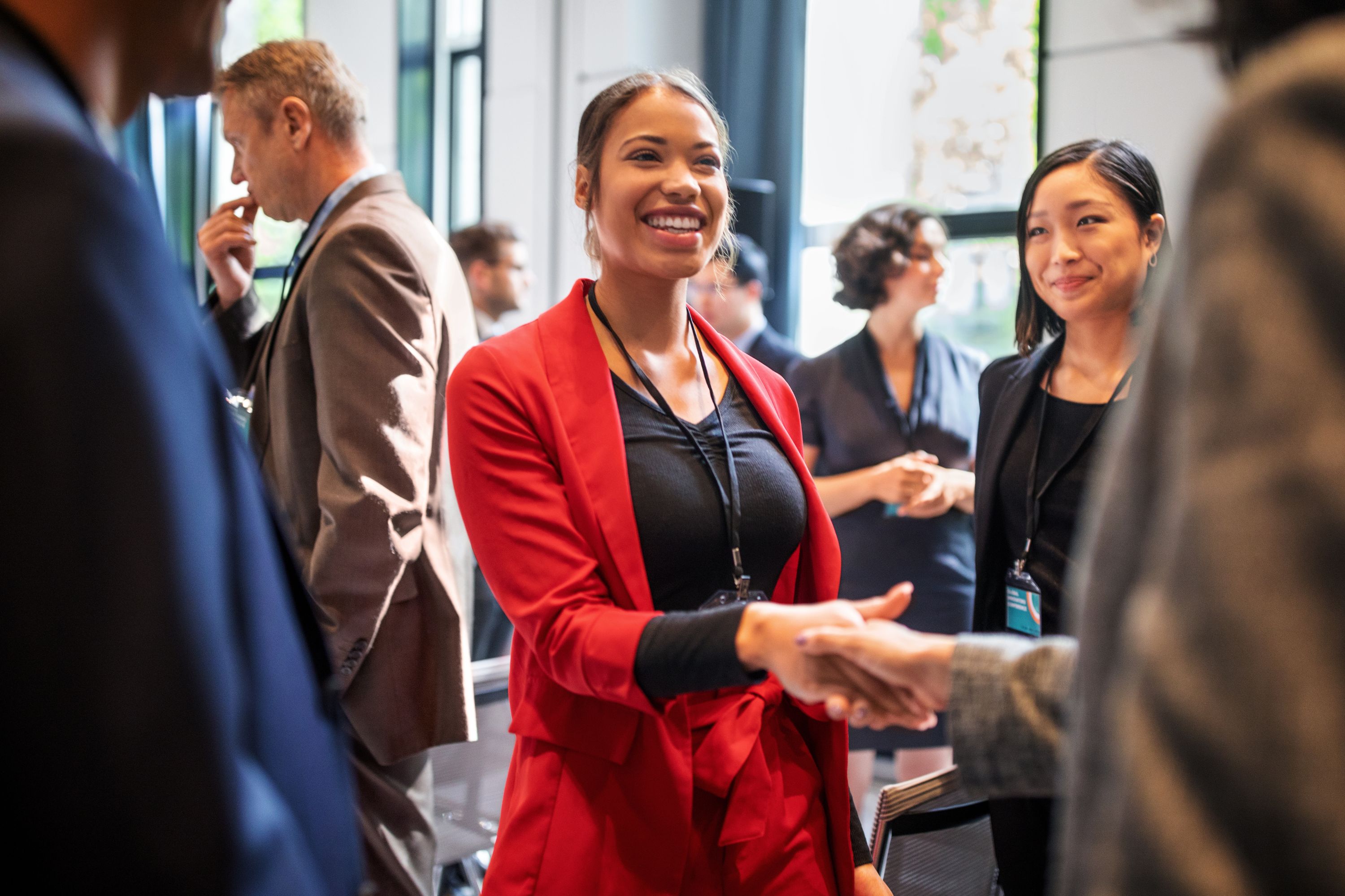 Young woman in red suit shaking hands at a business event
