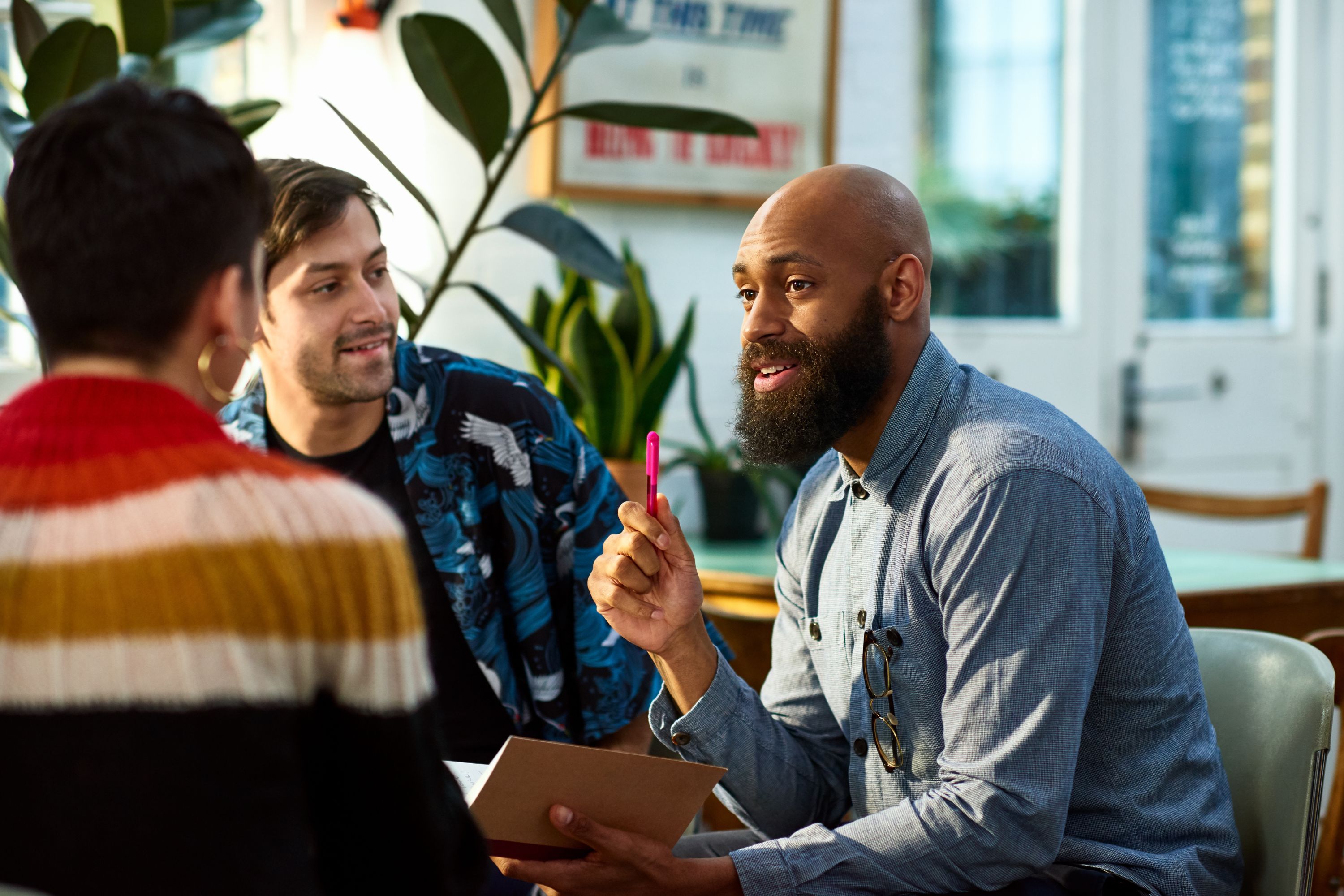 Three team members having casual meeting as one explains to the others