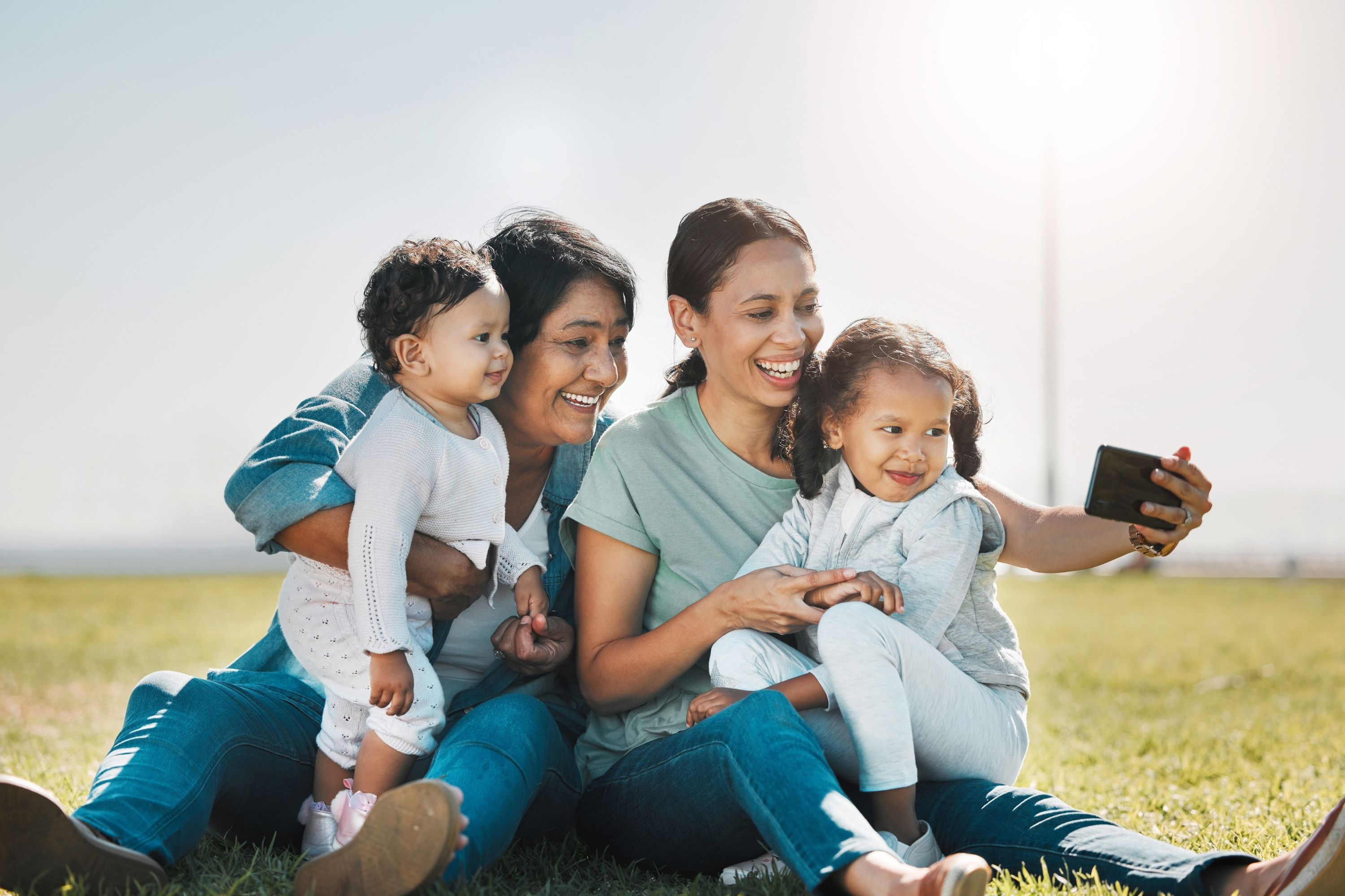 Family sitting on a grassy hill taking a selfie