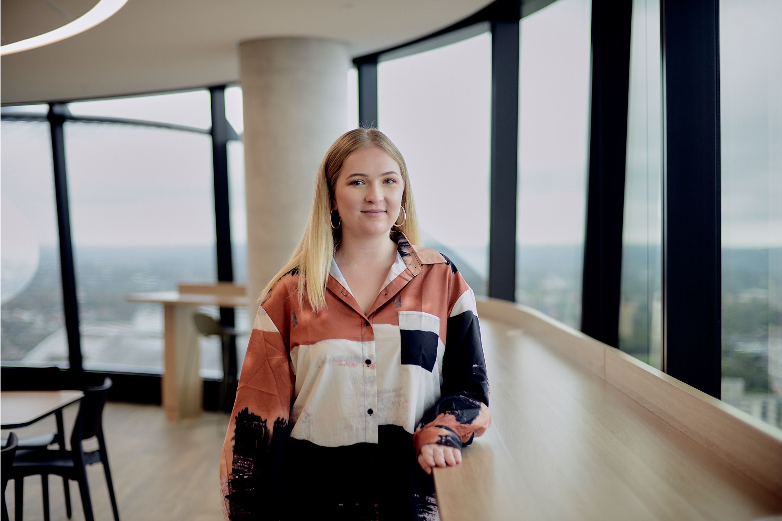 Tarsha Mcintyre in office setting with soft bright light wearing orange white and black jacket