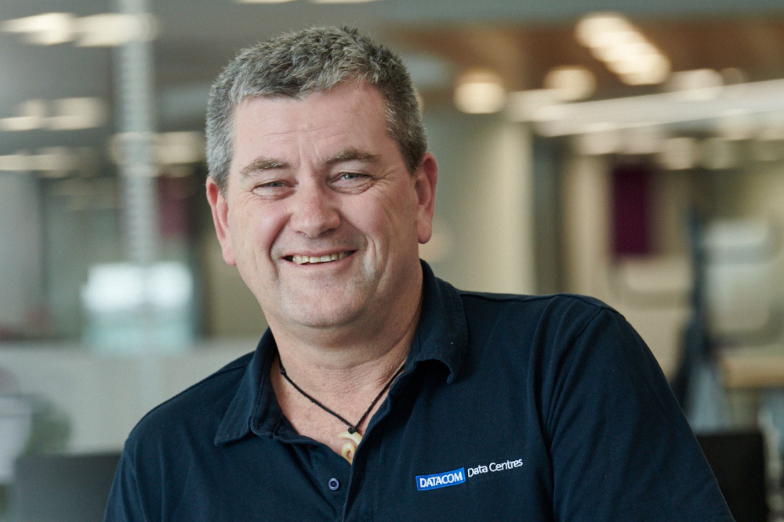 Portrait of Tom Jacob smiling with office out of focus in the background