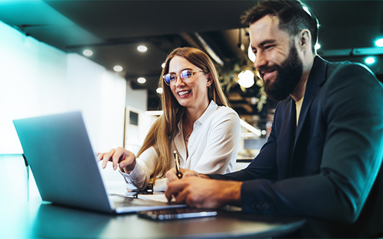 Two employees working together in front of a laptop