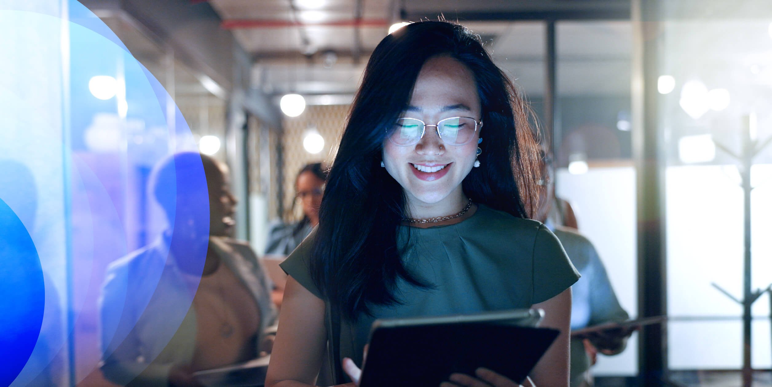 A smiling young female professional looking at a tablet screen.