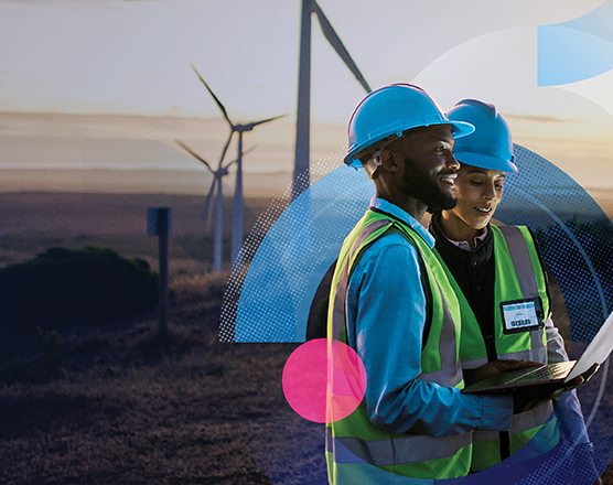 Two people with hardhats surveying in front of wind turbines